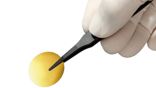 A gold-coated membrane held by a hand with a pair of tweezers