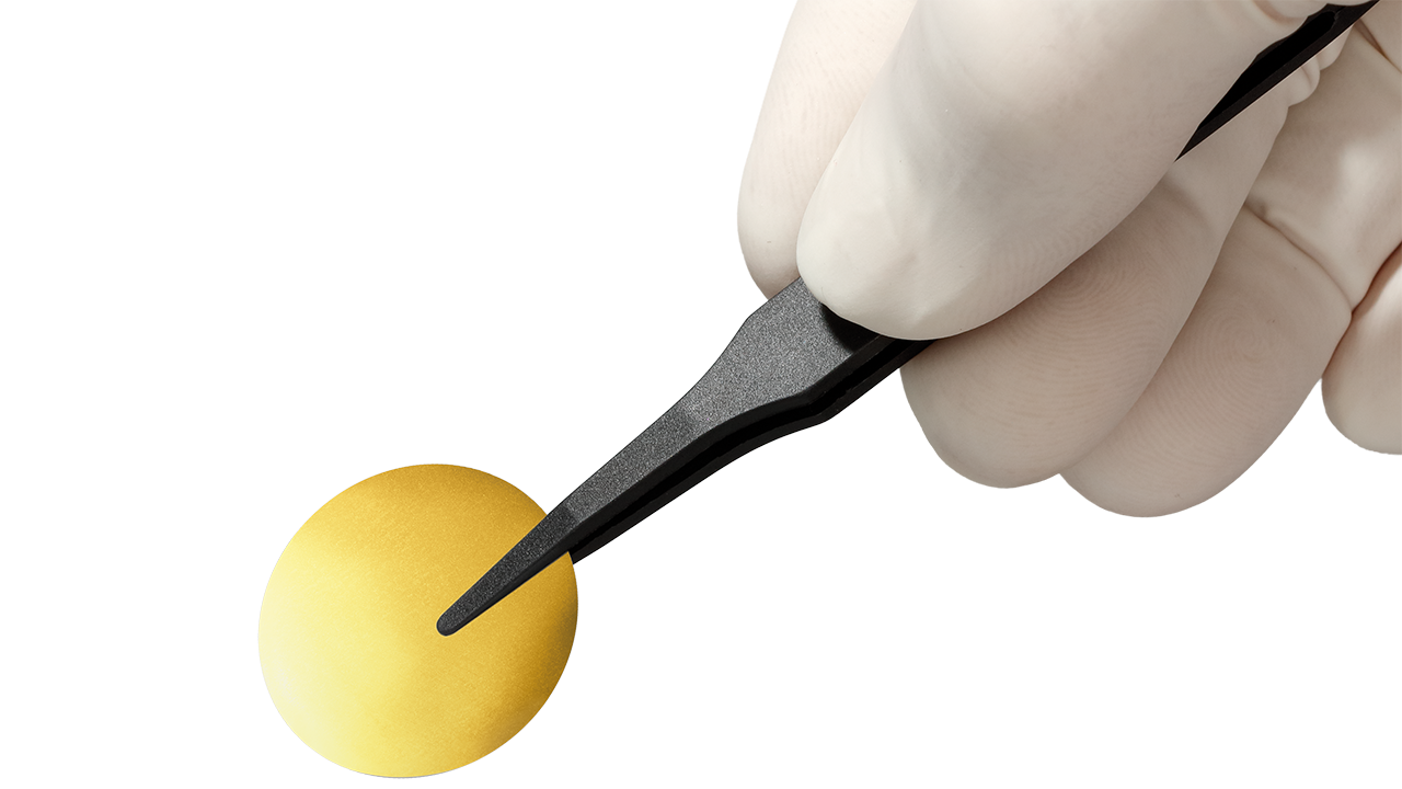 A gold-coated membrane held by a hand with a pair of tweezers